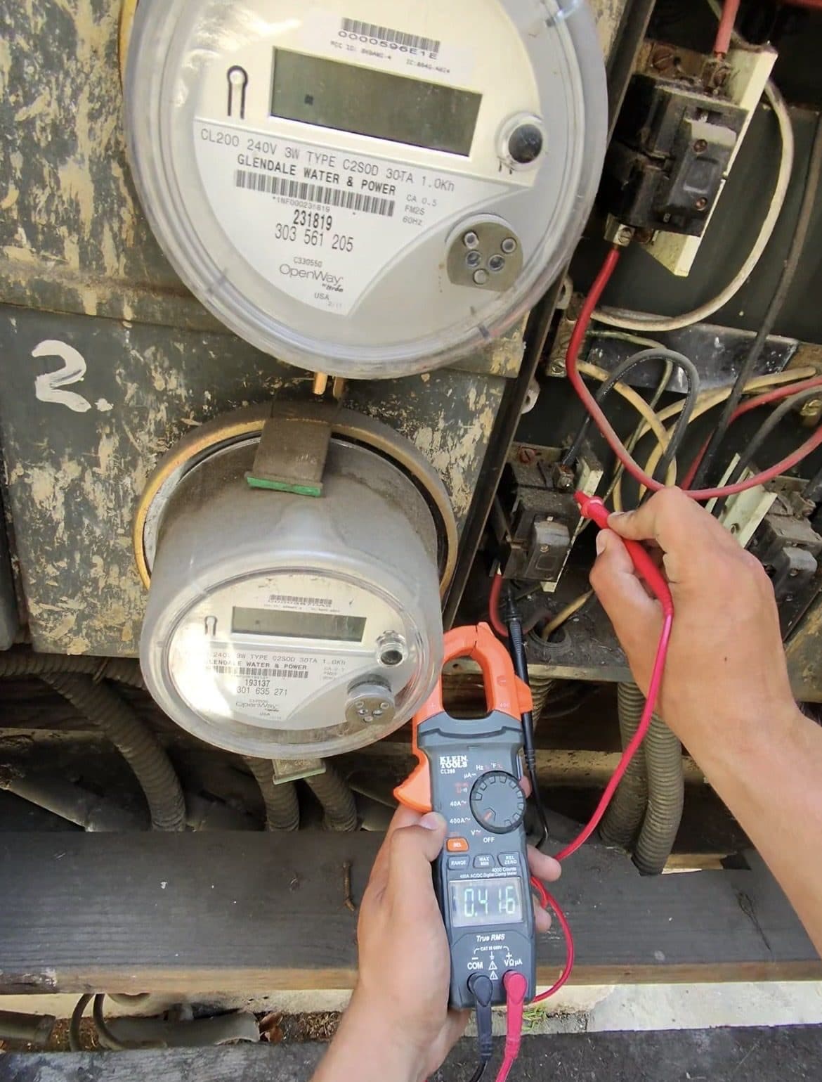 Electrician measuring voltage at a meter and main disconnect with a clamp multimeter
